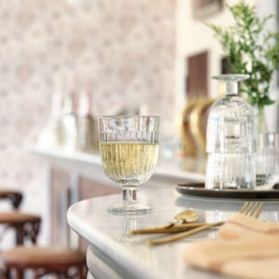 Photo d'un verre à pied strié la rochère sur un bar rempli de champagne